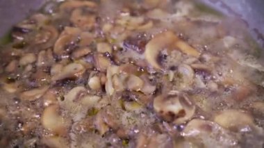 Donmuş şampiyon mantarları kızartma tavasında kaynıyor, yavaş çekim yakın plan..