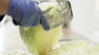 Özel lahana öğütücü bıçakla lahana doğrayan mavi eldivenli kadın.