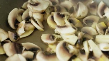 Taze şampiyon mantarları kızartma tavasında kızarıyor, yavaş çekimde yakın plan..