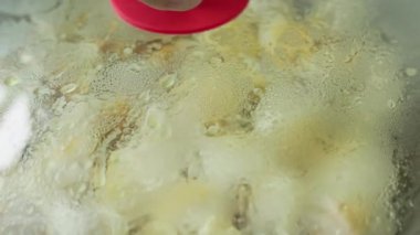 Hamur köfteleri kızartma tavasında, cam kapağın altında seçici odaklanma ve yavaş çekim ile kızartılır..