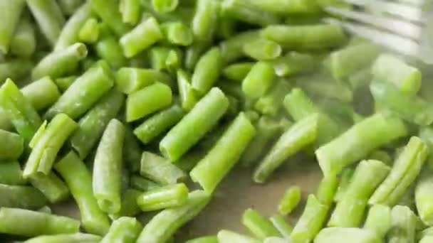 ステンレススチールフォークは フライパンにフライグリーン豆をかき混ぜ 選択的な焦点でフルフレームのクローズアップビュー — ストック動画