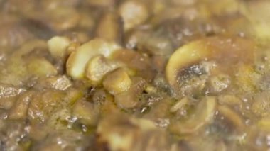 Donmuş şampiyon mantarları kızartma tavasında kaynıyor, yavaş çekim yakın plan..