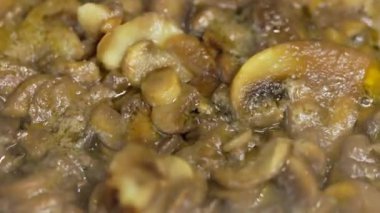 Donmuş şampiyon mantarları kızartma tavasında kaynıyor, yavaş çekim yakın plan..