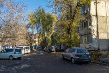 Kırgızistan, Bişkek 'te güneşli bir günde çok katlı bir apartmanın önüne park edilmiş birkaç araba var: 13 Kasım 2022