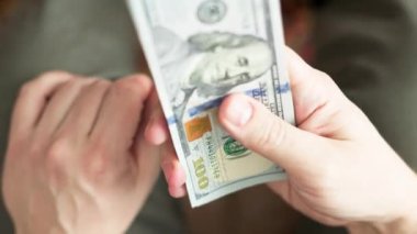 Beyaz eller 100 dolarlık banknotları sayıyor. Seçici odaklanma ve yavaş çekim ile yakın plan.
