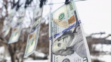 100 dolarlık banknotlar ipe asılı çamaşır mandallarıyla ve rüzgarda sallanıyor..