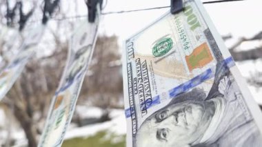 100 dolarlık banknotlar ipe asılı çamaşır mandallarıyla ve rüzgarda sallanıyor..