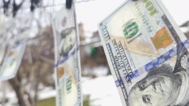 100 dolarlık banknotlar ipe asılı çamaşır mandallarıyla ve rüzgarda sallanıyor..