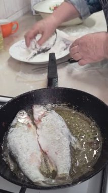 Kıdemli Kafkas kadınlarının elleri hamamböceğini una batırır ve ev mutfağındaki ocakta kızartmak için yağlı bir tavaya koyar..