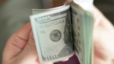 Beyaz eller, seçici odaklanma ve yavaş çekim ile yakın plan 100 Amerikan doları banknotlarını tutuyor ve kontrol ediyor.