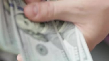 Beyaz eller 100 dolarlık banknotları sayıyor. Seçici odaklanma ve yavaş çekim ile yakın plan.