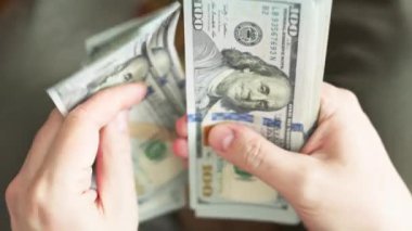 Beyaz eller 100 dolarlık banknotları sayıyor. Seçici odaklanma ve yavaş çekim ile yakın plan.