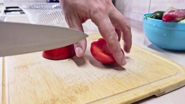 Beyaz eller, yerli mutfakta bambu kesme tahtasında kırmızı domates kesiyor. Geniş açılı, yavaş çekimde. Kullanıcı tarafından oluşturulan gerçek yaşam içeriği.