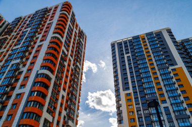 Mavi gökyüzü arka planında, beyaz bulutlu, düşük açılı yeni inşa edilmiş apartmanlar.