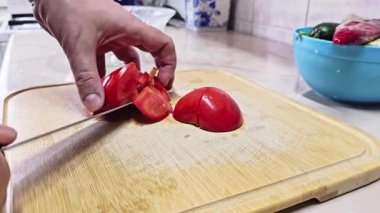 Beyaz eller, yerli mutfakta bambu kesme tahtasında kırmızı domates kesiyor. Geniş açılı, yavaş çekimde. Kullanıcı tarafından oluşturulan gerçek yaşam içeriği.