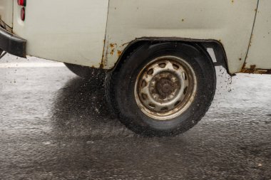 Şiddetli yağmurda asfalt yolda giden paslı Sovyet minivan..