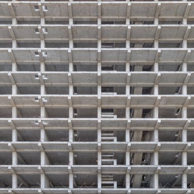 Gri bir cephe ve delikler desenli, çok katlı büyük bir apartman yapım aşamasında. Tam çerçeve arka plan. Düşük açı görünümü,