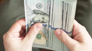 Beyaz eller 100 dolarlık banknotları sayıyor. Seçici odaklanma ve yavaş çekim ile yakın plan.