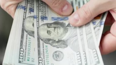 Beyaz eller 100 dolarlık banknotları sayıyor. Seçici odaklanma ve yavaş çekim ile yakın plan.