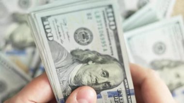 Beyaz eller 100 dolarlık banknotları sayıyor. Seçici odaklanma ve yavaş çekim ile yakın plan.