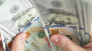 Beyaz eller 100 dolarlık banknotları sayıyor. Seçici odaklanma ve yavaş çekim ile yakın plan.