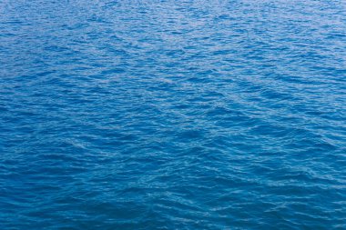 Elektrikli mavi su dalgalanmalarının sakin göl yüzeyinde büyüleyici bir şablon oluşturduğu sakin bir sahne.