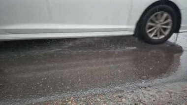 Yağışlı yağış sırasında asfalt üzerinden geçen beyaz araba - yavaş çekim yakın görüş