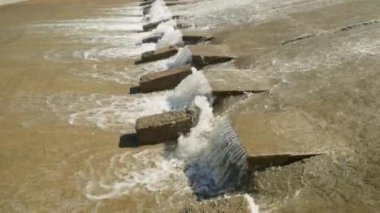 Bir sıra paraşüt, beton su sızıntısı kanalındaki blokları dengeleyerek suyun akışını yavaşlatır..