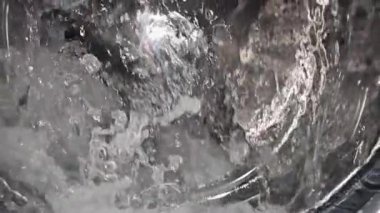 Çamaşır makinesine su sıçratan süper yavaş çekim, cep telefonuyla yapılan videodaki ağır ara polasyon objeleri.