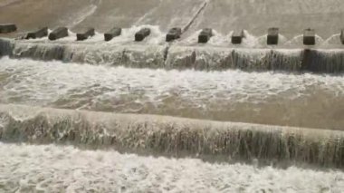 Bir sıra paraşüt, beton su sızıntısı kanalındaki blokları dengeleyerek suyun akışını yavaşlatır..