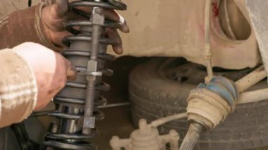 Olgun beyaz bir tamircinin nasırlı elleri bobin yay bağlarını DIY araba tamiri sırasında ingiliz anahtarıyla büker. Yakın çekim..