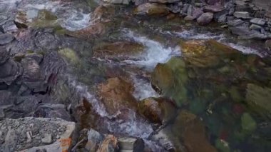 Dağların altındaki dağ nehri güneşli bahar akşamında nehir boyunca eğik bir şekilde sola dönüyor.