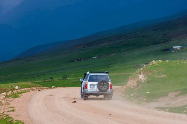 Kırgızistan Semenovskoye Boğazı 'nda 5 Temmuz 2023' te fırtına öncesi bulutlu gökyüzü ile uzak dağ geçidinde maceralı bir off-road yolculuğu.