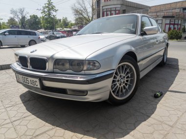 Bishkek, Kırgızistan 'ın güneşli yaz caddelerinde mükemmel bir şekilde kurtarılmış gümüş BMW 740i E38 - 9 Haziran 2023