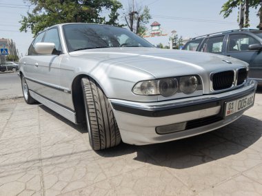 Bishkek, Kırgızistan 'ın güneşli yaz caddelerinde mükemmel bir şekilde kurtarılmış gümüş BMW 740i E38 - 9 Haziran 2023