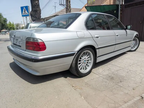 Bishkek, Kırgızistan 'ın güneşli yaz caddelerinde mükemmel bir şekilde kurtarılmış gümüş BMW 740i E38 - 9 Haziran 2023