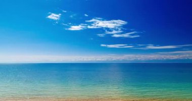 Güneşli yaz gününde Issyk-kul Dağı 'nın üzerinde yüzen ince bulutlar. Suda hafif dalgalanmalar ve ufukta dağ silsilesi var.