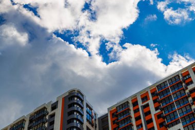 Mavi gökyüzü arka planında beyaz bulutlu, yeni inşa edilmiş bir apartman..