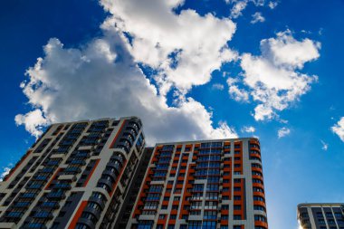 Mavi gökyüzü arka planında beyaz bulutlu, yeni inşa edilmiş bir apartman..