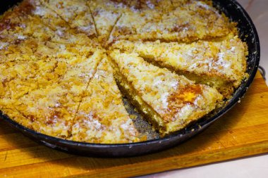 Yerel elmalı turta, siyah yuvarlak dökme demir tavayla dilimlenmiş, yakın plan.