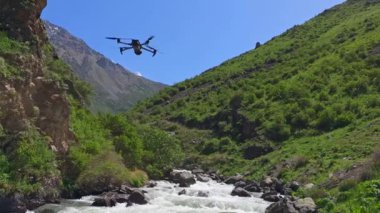 Quadcopter drone güneşli yaz gününde dağ nehrinin üzerinde süzülüyor.