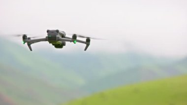 Çiseleyen yaz gününde, kuadkopter dronu sisli yeşil dağların üzerinde yavaşça uçuyor..