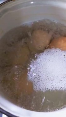 Dört tavuk yumurtası beyaz mayalı çelik güveçte kaynıyor, yakın plan.