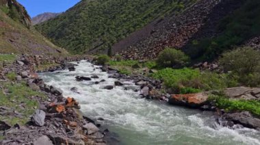 Güneşli yaz gününde dağlık vadide büyük kayalıkları olan dağ nehri..