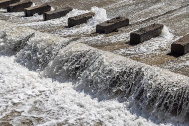 Bir sıra paraşüt, beton su sızıntısı kanalındaki blokları dengeleyerek suyun akışını yavaşlatır..