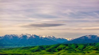 Yaz akşamı bulutları karla kaplı sıradağların üzerinde uçuyor yeşil eteklerle, insansız hava araçlarıyla