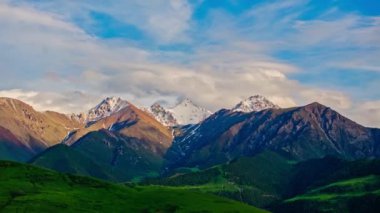 Kırgızistan 'da yaz akşamında bir dağ sırasının tepesinde karla kaplı bir dağ, kamera hareketleriyle hava aşırı hızında..