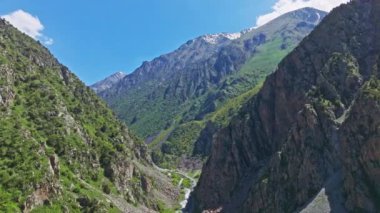 Berrak, mavi gökyüzünün altındaki yemyeşil dağların nefes kesici ve çarpıcı manzarası.