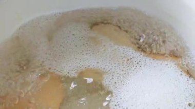 Dört tavuk yumurtası beyaz mayalı çelik güveçte kaynıyor, yakın plan.