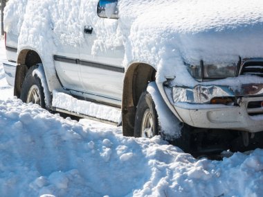 Kar, güneşli kış gününde eski beyaz SUV arabasıyla kaplıydı.